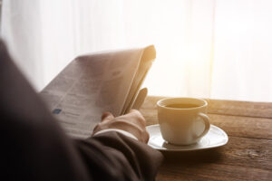 man enjoys cup of coffee while reading the newspaper